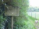 Footpath with sign:
'ST NICHOLAS C OF E
PRIMARY SCHOOL
PRIVATE GROUND
SCHOOL USE ONLY
PUBLIC PLEASE KEEP
TO EDGE OF FIELD'
Low chainlink fence on right.
Dog on footpath.
