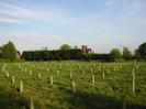 Field with young trees.
Row of trees in the distance partly obscures a large house.
Church spire just visible on the skyline.