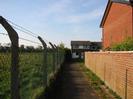 Footpath with chainlink fence on the left, brick wall and house on the right.
Field on the left used to be Taplow Vineyard, but now has grass and young trees.