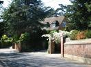Looking West on Rectory Road.
High brick walls on the right, with large trees behind.
Part of house visible through the trees.