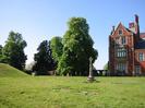 The old churchyard beside Taplow Court.
Saxon burial mound on the left.
Trees and grave markers in the background.
Memorial and gravestones in the foreground.
Part of Taplow Court on the right: large house in red brick with stone-mullion windows.