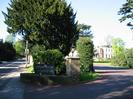 The entrance to Taplow House Hotel.
Road on left with streetlight and 'KILL YOUR SPEED' sign.
Large trees.
Engraved stone hotel sign.
Brick pillar with lantern.
Georgian-style hotel in the distance on the right.
Red tarmac driveway.