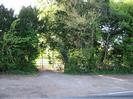 Entrance to field on west side of Berry Hill.
Gravel area beside road.
Metal gate leading to field.
Trees on either side.