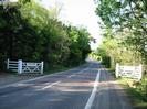 Looking north on Berry Hill.
White traffic-calming `gate features' on each side of road.
Sign on each gate reads `TAPLOW Please drive carefully'.
Stripes of red tarmac across road.
Hedges and trees on both sides of road, which rises gently into the distance.