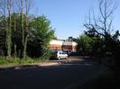 Rear entrance of Altwood BMW dealership on Bath Road.
Trees on both sides of gate.
People and parked cars.