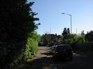 Looking south on Berry Hill.
Hedges on both sides of road.
Cars queued for traffic lights at Bath Road junction.
Neuk House on far side of Bath Road.
Tall streetlights.