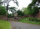 Driveway with wrought-iron gates set in high brick wall.