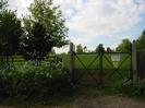 Field with high wire fence and gate.
Small trees near fence.