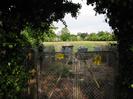 Metal gates with grey boxes and field beyond.
Trees on the horizon.