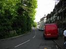 Looking south on Mill Lane.
Large trees on left.
Row of three-storey houses on right.
Junction with A4 Bath Road in the distance.
