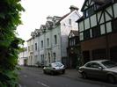 Looking south on Mill Lane.
Row of three-storey terraced houses.
Those on the left are white painted.
Those on the right have brick at ground-floor level and white paint with brown timbers above.
The disused Skindles Hotel is visible in the distance.