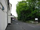 Looking north on Mill Lane.
Disused hotel building on the left: cream painted with black pipes.
Large trees on the right.
Sign at entrance to car-park: "MALLARDS REACH RESIDENTIAL CAR PARK. PRIVATE"