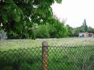 Low chainlink fence with field and trees beyond.
Low brick building with large pipes on the right.