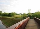 Wooden footbridge with river and fields on left.
