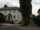 White house with dark slate roof.
Tall trees.
Gravel drive between houses.