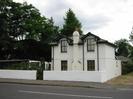 The Lodge.
White-painted two-storey house with unusual low roof and gables over upper windows.
Low white wall around garden.