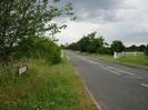 Road with grass verge and bushes on left.
Roadsign for Boundary Road.
Grass area on right with trees.
White traffic-calming gate feature.