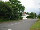 Road with trees and houses on the left.
Grass verge on the right.