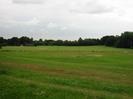 Grassy slope down towards playing field.
Trees in the distance.
