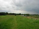 Rough grass with path.
Road with cars on right.