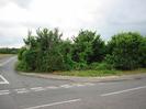 Road junction.
Pavement with grass and bushes behind.
Back of Give Way sign at junction.