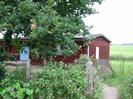 Low wooden clubhouse with fence and trees in front.
Grassy area behind.