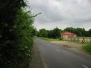 Institute Road, with footpath and bushes on the left.
Playing field and sport club on the right.
Bank of trees in the distance.