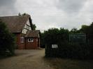 Taplow and Hitcham W.I. Hall.
Concrete driveway with hedges on each side.
Hall has red bricks at ground-floor level, and is rendered with black timbers on the end wall under the roof.
Porch with low steps.
Private Car Park sign.
Three overhead cables. 