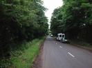 Looking south on Station Road.
Large trees on both sides.
Parked cars on the right.
