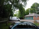 Block of garages.
Fence and trees on the left.
Parked van and car.
Street-light on the right.