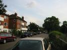 River Court flats on left.
Parked cars along River Road.
Large trees in the distance.