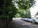 Looking north on River Road, to the junction with the A4 Bath Road.
Fence and trees on left.
Parked cars on right.