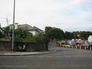 Looking north across the Bath Road to Mill Lane.
Skindles Hotel visible over the end of the bridge parapet on the left.
Line of concrete bollards around car dealership on right.
Gasometer just visible through trees in the distance.