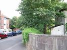 River Road, with Bridge Court flats on left.
End of Maidenhead Bridge parapet on right, with derelict houses behind it.
Trees.
Parked cars.