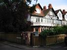 The corner of Ellington Road where it joins River Road.
Noticeboards and post boxes.
Cornerways: black and white three storey house behind wooden fence.