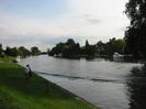 River Thames.
Grassy bank on left with people and moored boats.
Trees and boats on far bank.
