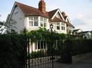 The Riverbank House.
Two storey house with pink pebbledashed walls and white-painted windowframes.
Red tile roof.
Gravel drive with high wrought-iron gates