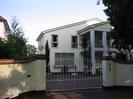 Folliotts.
Large white house with Mediterranean-style portico.
White iron gates set between high light-coloured walls.