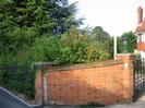 Hedge, red-brick wall, and flagpole at entrance to Red House.