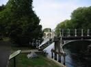 The western end of the Guards Club Island footbridge, with part of Maidenhead Bridge visible beyond it.
Trees along the river bank on the left.
Information notice in the foreground.