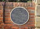 Sign describing Guards Club Park:
"Site of the Brigade of Guards Boat Club in the Edwardian era, when Maidenhead was a popular riverside resort.
This park was created by Maidenhead Civic Society to commemorate the Silver Jubilee of Queen Elizabeth II 1977"
Sign is mounted on red-brick wall just inside the park.