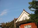 Decorative gable-end with fretwork, half-round window, and terracotta dragon on ridge.