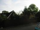 High wooden fence with house visible beyond.