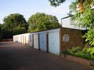 Block of garages with light-blue doors.
Trees.
Sign on garages: "NO PARKING AT ANY TIME GARAGES IN CONSTANT USE"