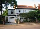 White painted house with black details.
Red tile roof.
Small tree in front garden.
Low walls.