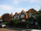 Two-storey houses with dark red tile roofs.
Victorian-style street light set among trees.