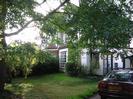 White house with grass and large tree in front garden.
Car parked in driveway.