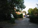 Service road with trees and block of garages at far end.
Telephone wires.