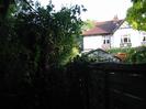 White house with red tile roof and black timberwork.
Greenhouse.
Trees.