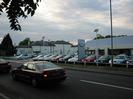 Road with car dealership and boarded-up hotel on far side.